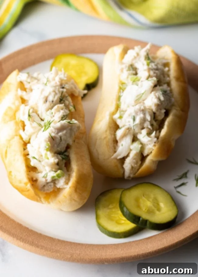 crab roll sandwiches with crab meat salad recipe and pickles on a plate