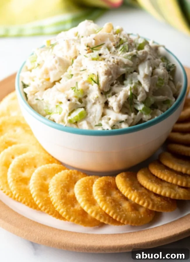 a bowl of seafood salad with chopped celery and dill with crackers