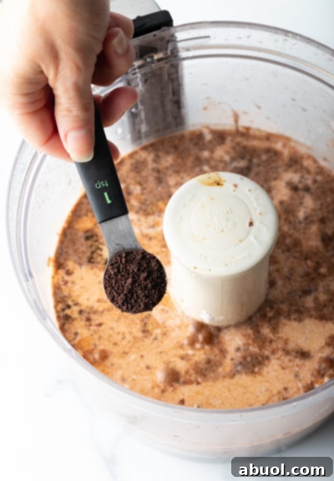 The chocolate pudding layer being spread evenly over the cream cheese layer.