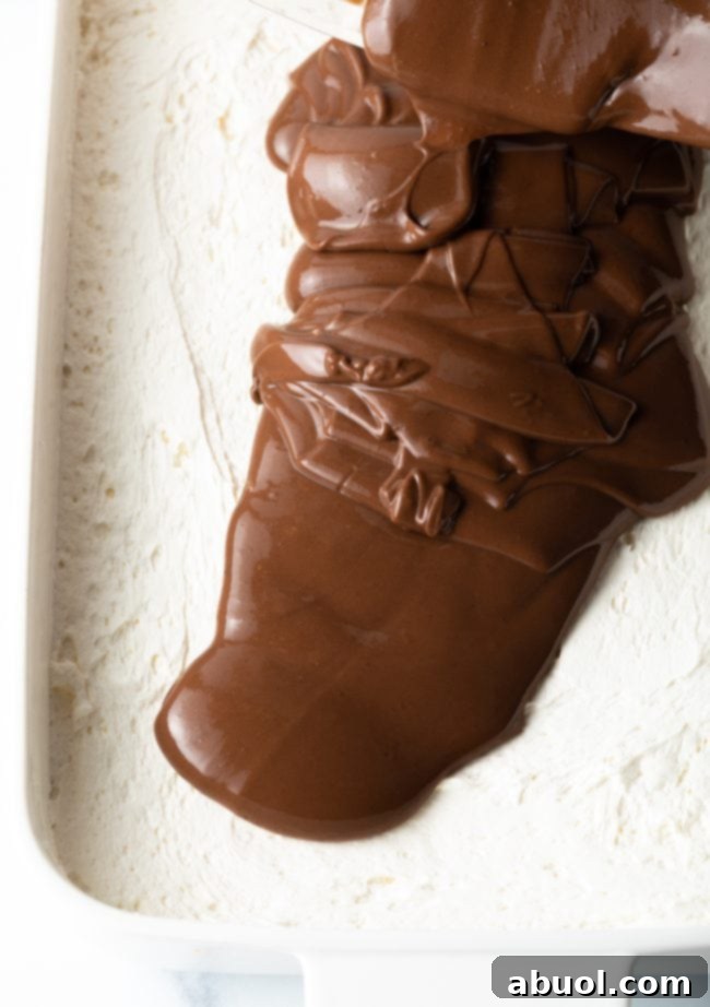 The final layer of whipped topping being gently spread over the chocolate pudding.