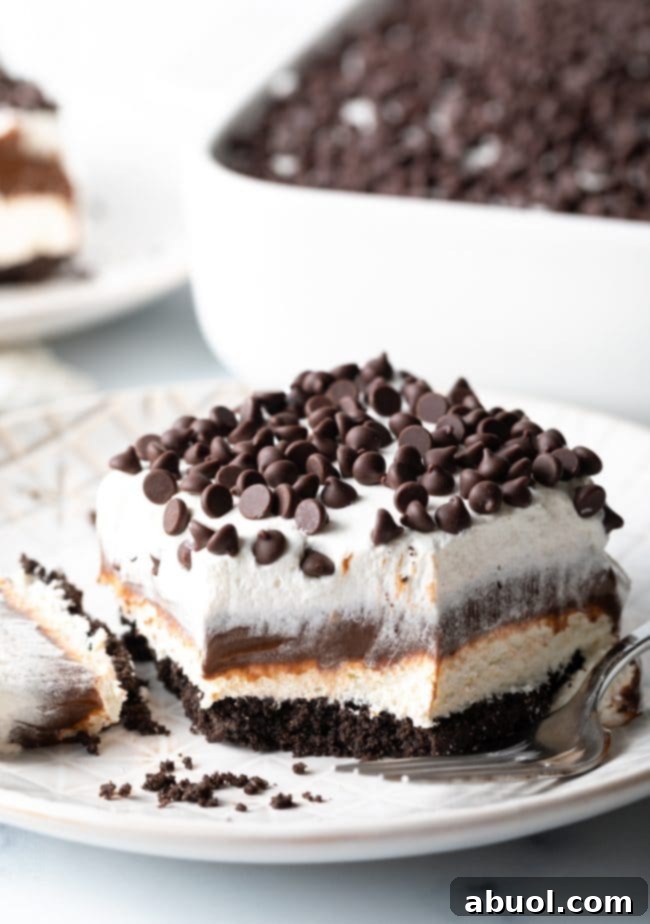 A slice of no-bake chocolate lasagna with a bite taken, clearly showing the crisp Oreo crust, the two creamy layers, and the whipped topping.