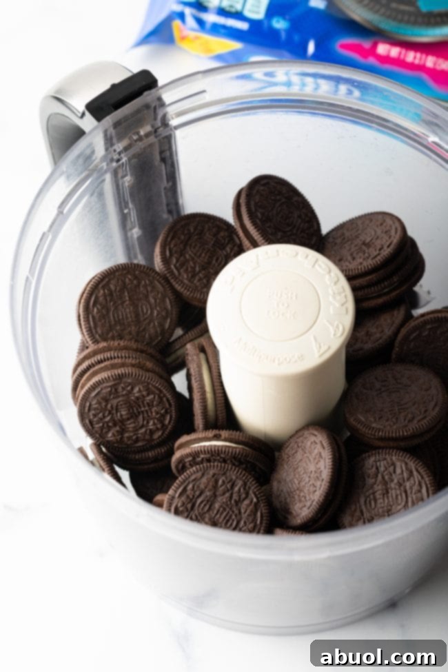 Oreo cookies being crushed in a food processor, showing the process of making the crust.