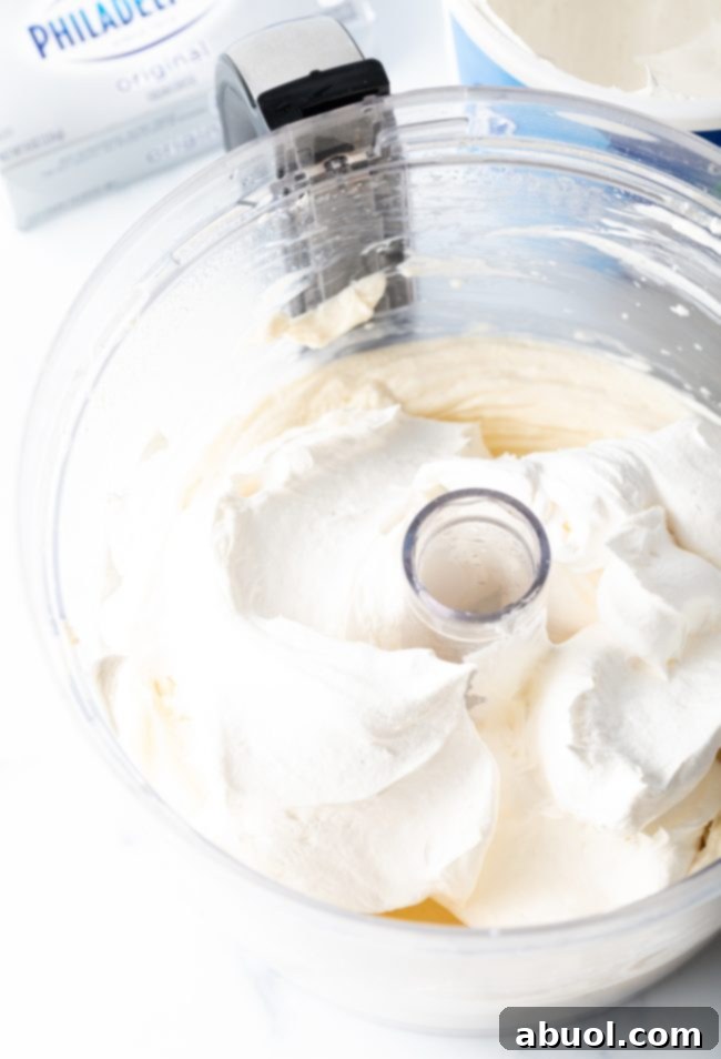 The smooth cream cheese layer being carefully spread over the chilled Oreo crust.