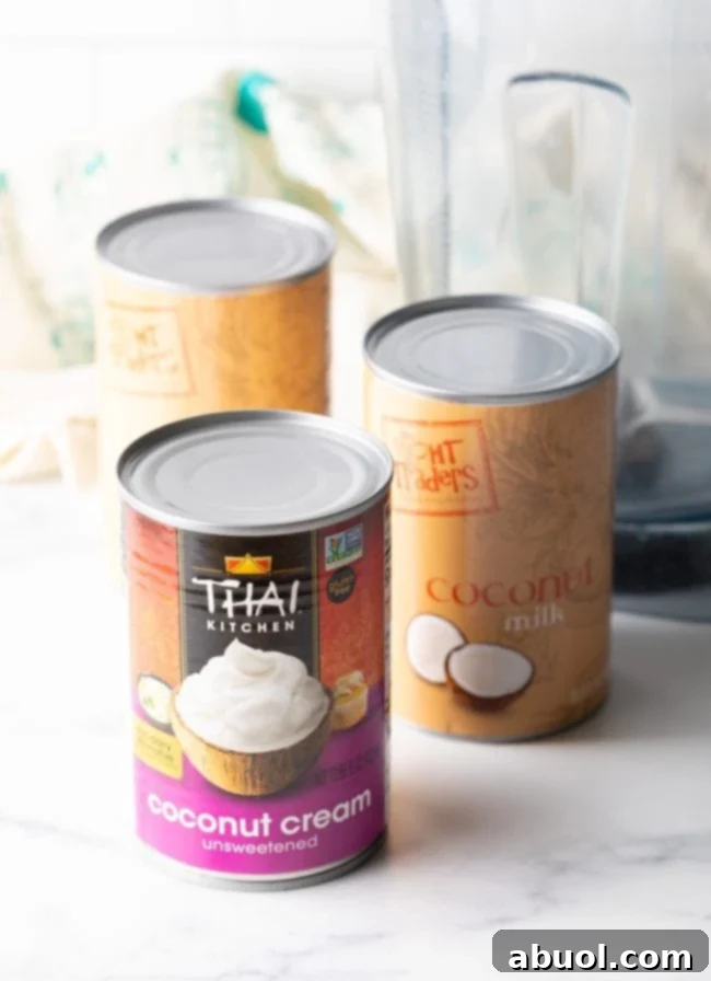 Several cans of full-fat coconut cream neatly stacked, highlighting an essential ingredient for the recipe.