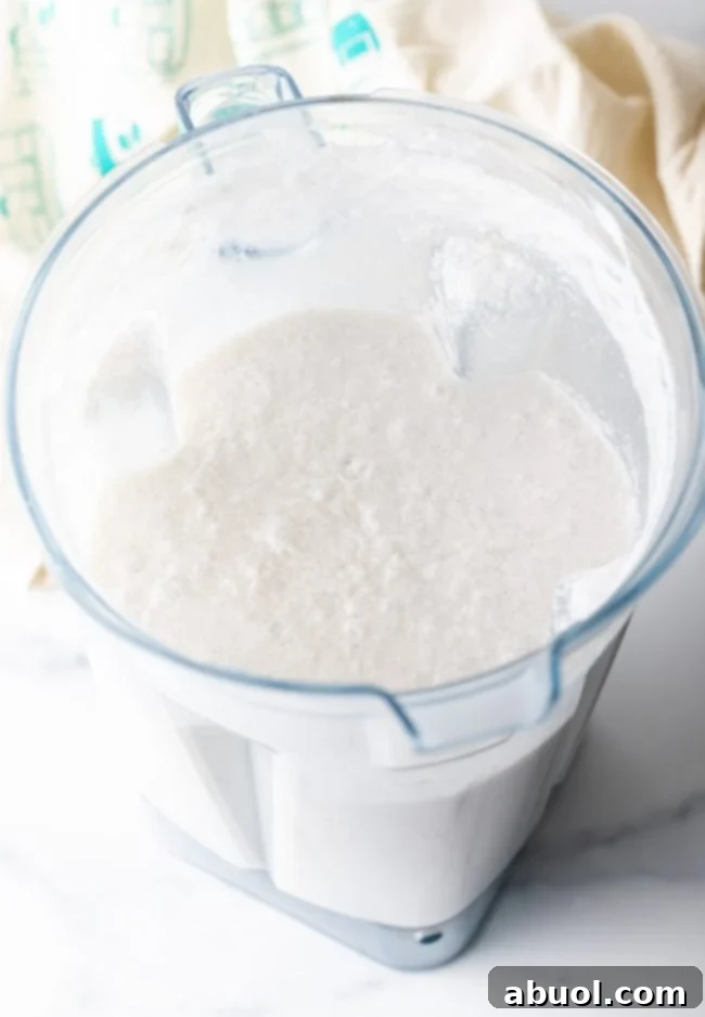 A smooth, blended mixture of coconut milk and sugar in a glass container, ready for the next step of ice cream making.