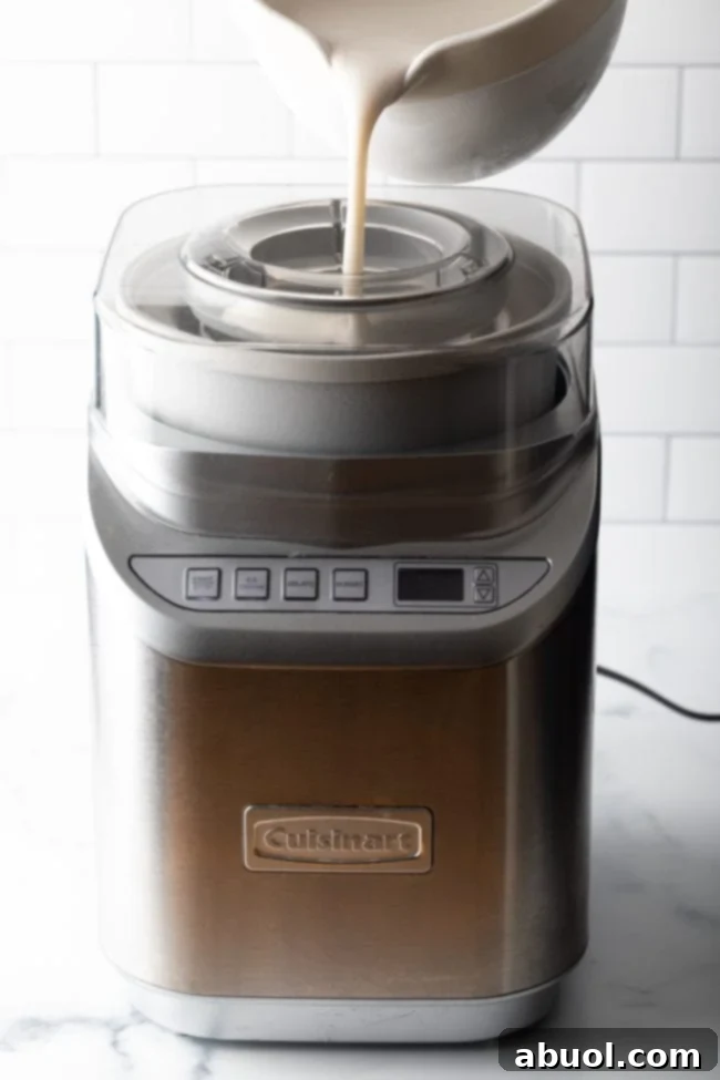 The cold coconut milk ice cream mixture being poured into an ice cream machine for churning.