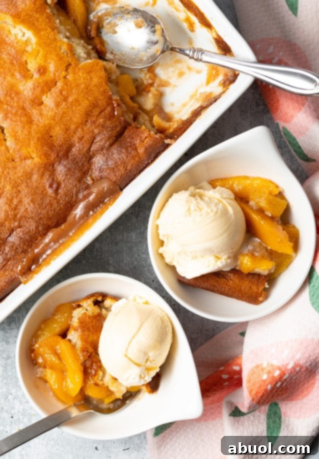 Two bowls of Bisquick peach cobbler, one with vanilla ice cream, ready to serve