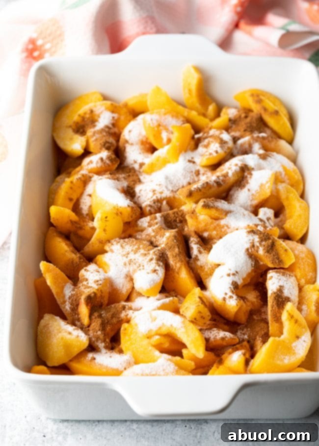 Sliced peaches coated with sugar and spices in a baking dish