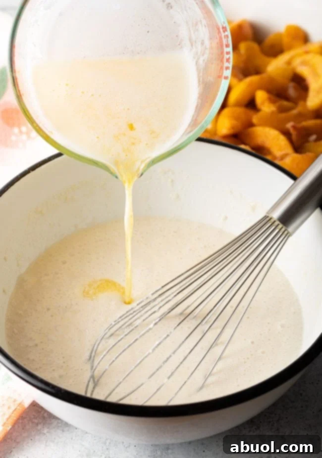 Whisking melted butter into the Bisquick batter for the cobbler topping