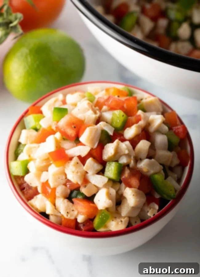 side view of bowl with conch salad filled with authentic Bahamian food ingredients, garnished with lime wedges