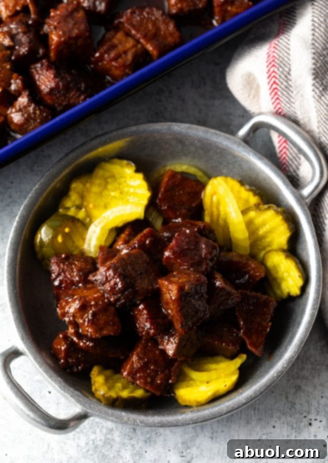 Oven-Baked Brisket Burnt Ends 2 Brisket Burnt Ends (Oven Recipe) - A bowl of burnt ends in bbq sauce with pickles.