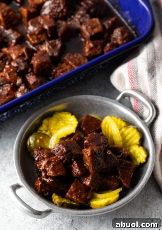 Oven-Baked Brisket Burnt Ends 11 Overhead top chunks of brisket burnt ends in a metal bowl with sliced bread and butter pickles.