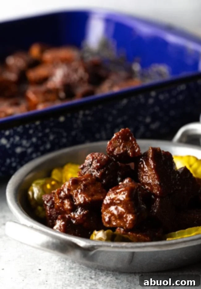 Oven-Baked Brisket Burnt Ends 3 Chunks of brisket burnt ends in a metal bowl with sliced bread and butter pickles.
