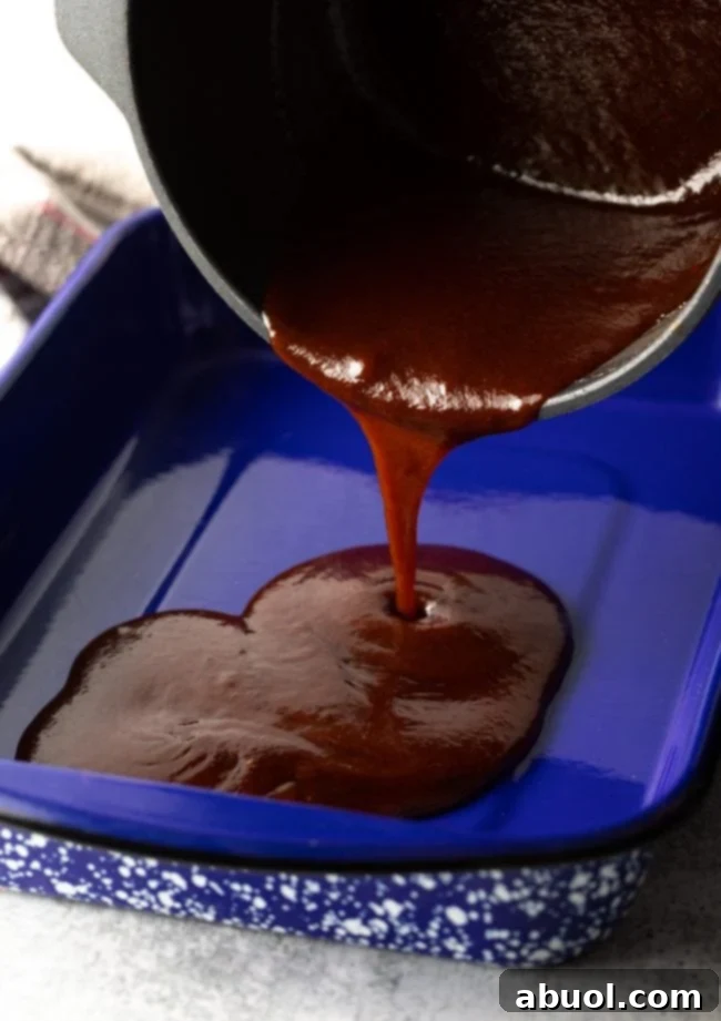 Oven-Baked Brisket Burnt Ends 7 Pouring barbecue sauce into a large blue pan.