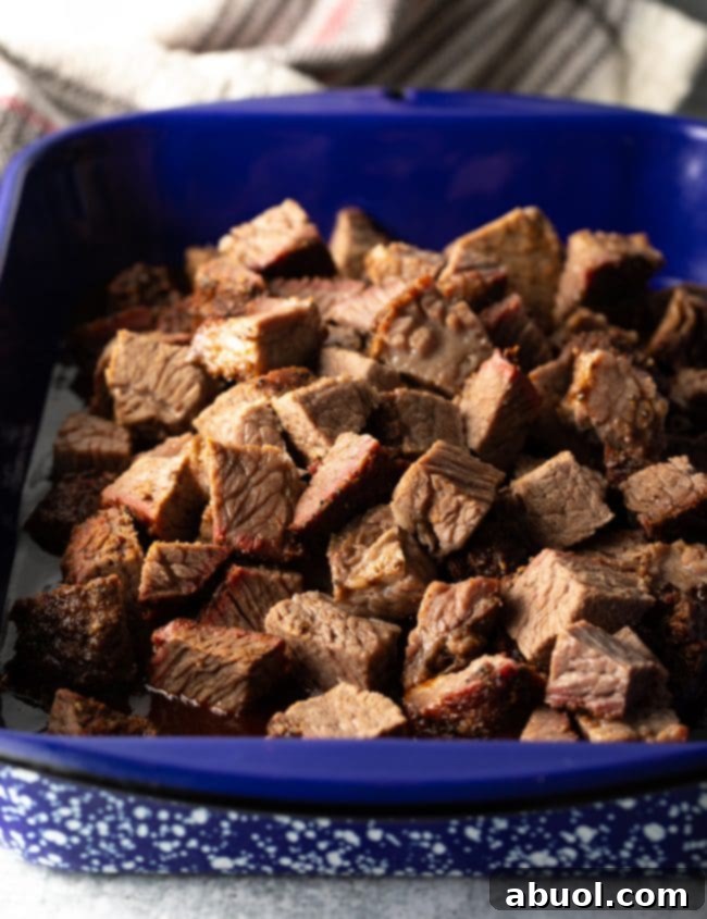 Oven-Baked Brisket Burnt Ends 8 Chunks of smoked brisket in the bbq sauce in a blue pan.