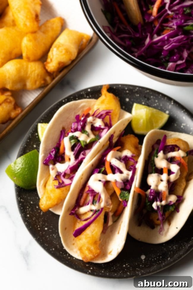 Overhead view of fish tacos with fresh slaw and a creamy taco sauce