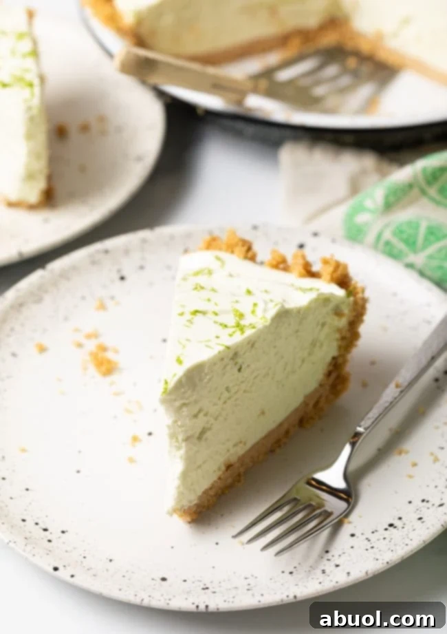 Slice of no-bake key lime pie on a white plate with a fork. 