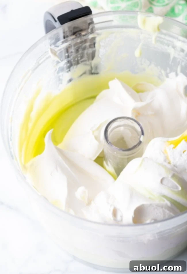 Adding cool whip to the key lime filling in the food processor.