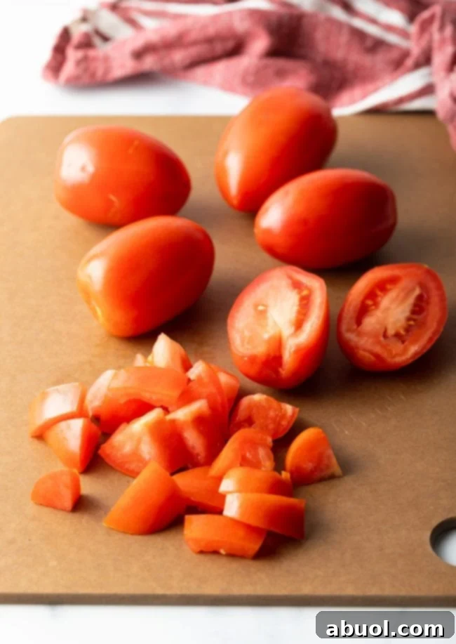 Fresh tomatoes, perfectly chopped, ready for cooking on a clean cutting board.