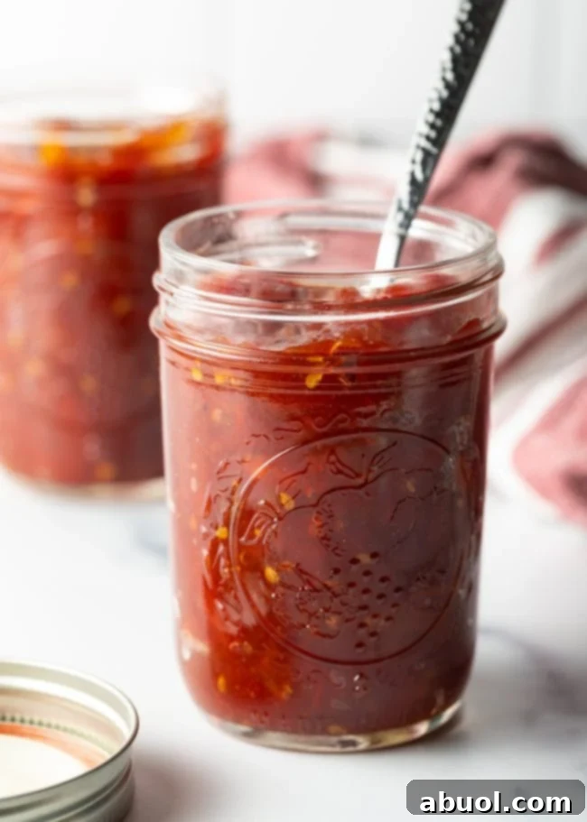 A beautifully finished jar of homemade tomato jam, with a spoon resting inside, ready for enjoyment.