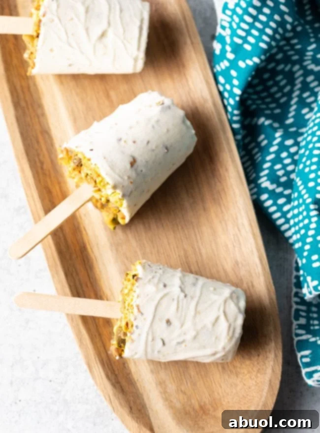 Platter of homemade Kulfi ice cream pops, garnished with crushed pistachios, ready to serve.