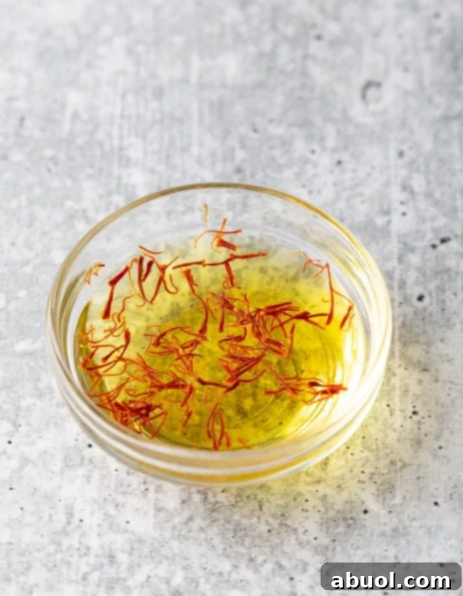Small bowl containing saffron threads soaking in warm water, releasing their golden color.