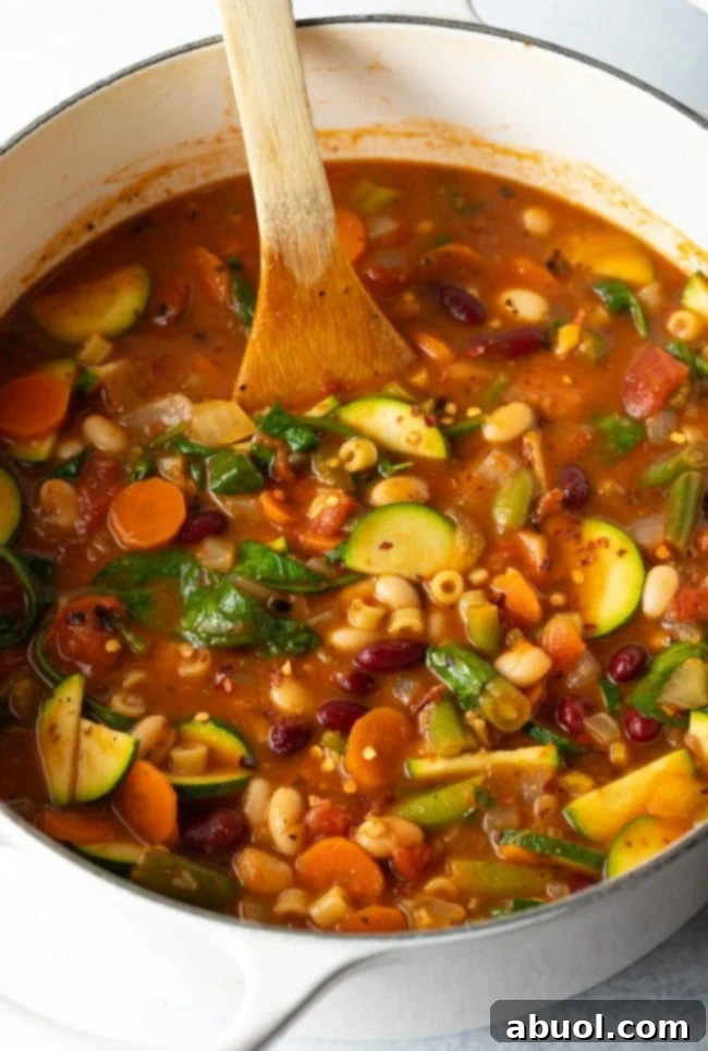 Overhead side view of a vibrant homemade minestrone soup, packed with colorful vegetables and pasta.