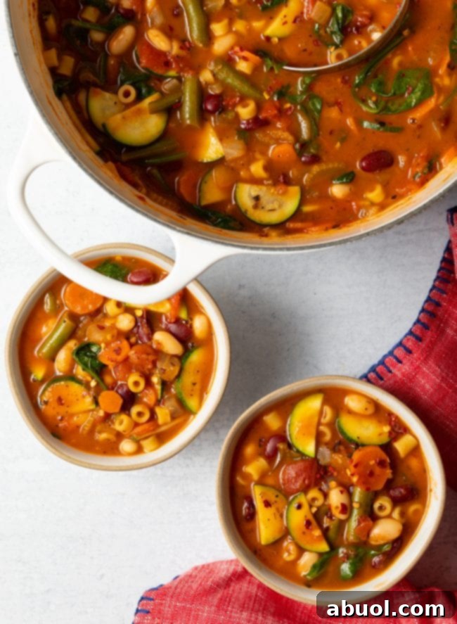 An inviting overhead view of a large pot of Olive Garden Minestrone Soup, flanked by two full bowls ready to be enjoyed.