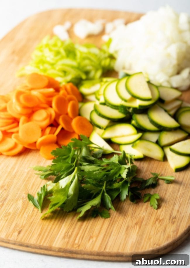Cutting board with freshly chopped carrots, zucchini, onion, and celery, ready for the soup.