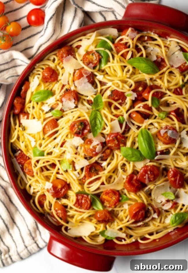 Spaghetti pasta with roasted cherry tomatoes coating them in a large pot.