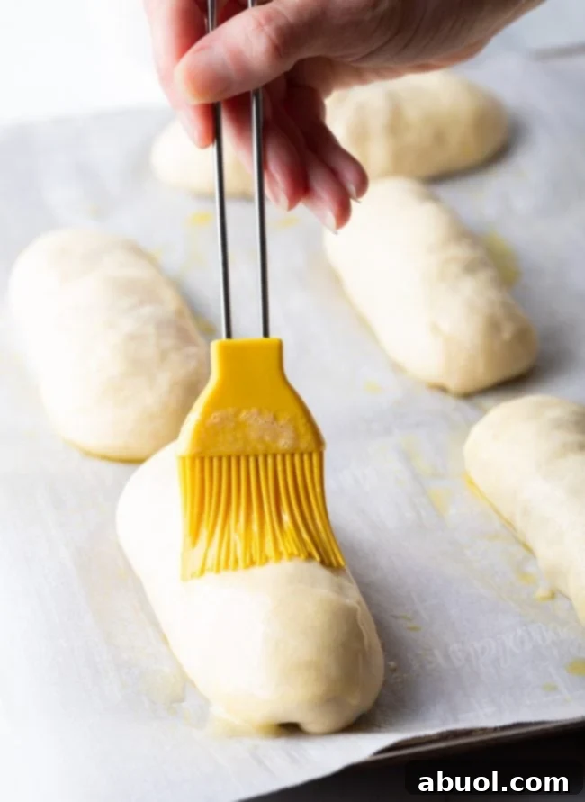 Brushing pepperoni rolls with butter.