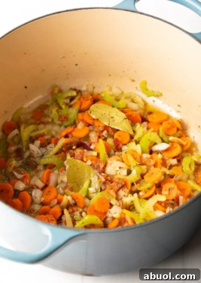 Vegetable trinity of celery, carrots, and onions cooking in a large pot
