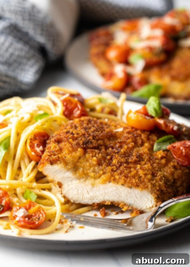 cut breast showing meat inside, on a plate with fork and pasta