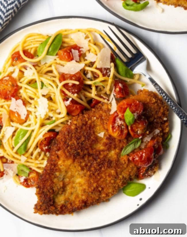 overhead view of finished plate with crunchy Panko Italian breasts cut thin, on a plate with spaghetti and cherry tomato sauce on the side