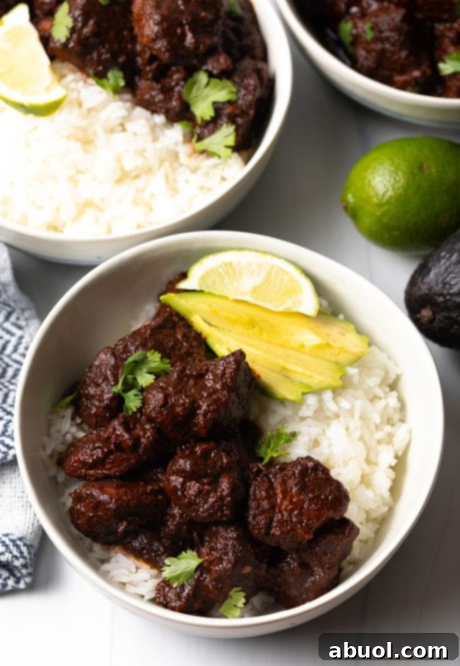 New Mexican Red Chile Pork - finished bowl top view with white rice, red chile carne adovada, slices of avocado, and lime wedge