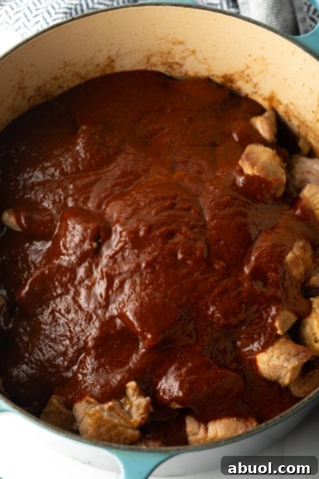seared pork covered in red chile sauce in a pot