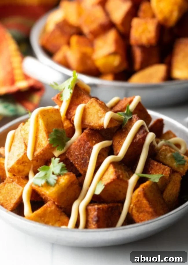 bowl of finished patatas bravas recipe close up with creamy aioli and chopped cilantro