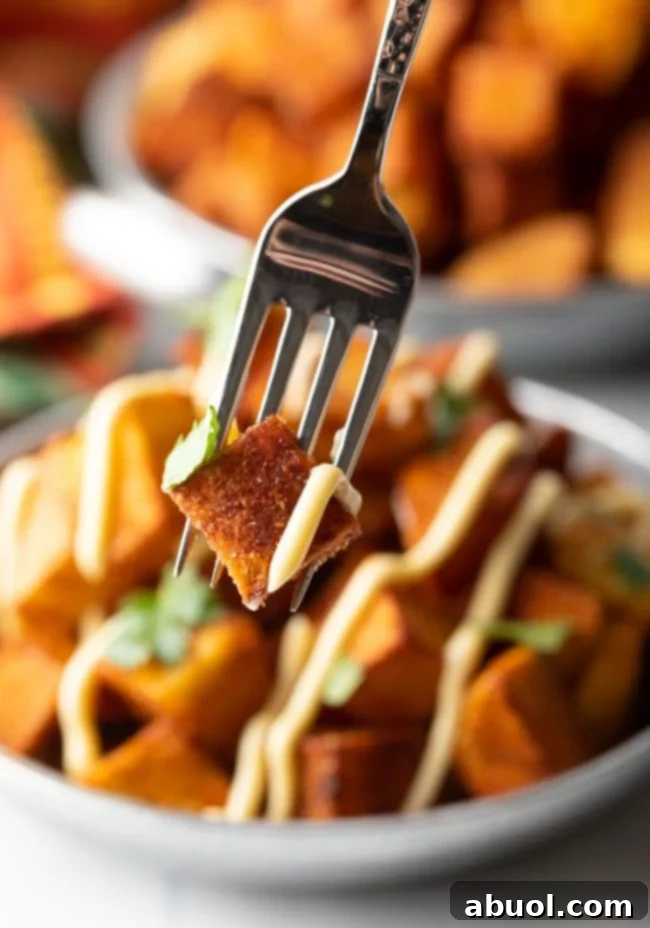 fork with single Mexican fried potato and bit of sauce and cilantro - Papas Bravas