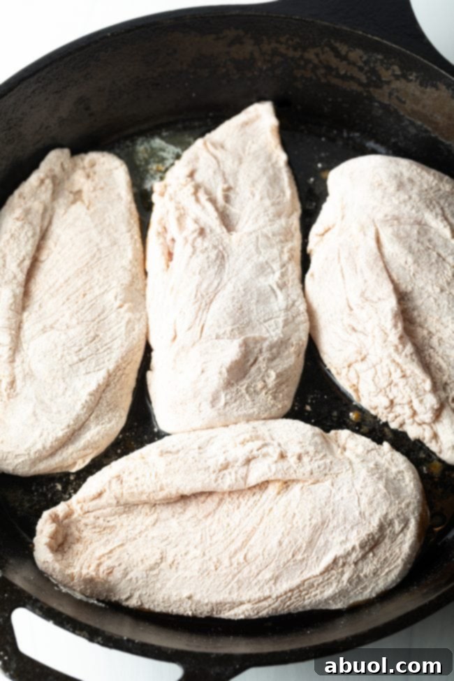 cast iron skillet overhead view 4 flour coated breasts in butter
