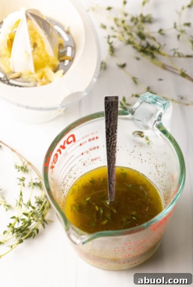 glass measuring cup with oil, garlic, lemon, and seasonings