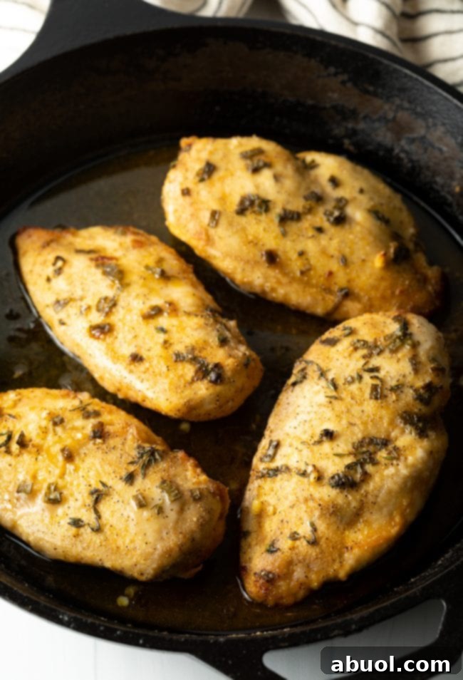overhead top view oven baked chicken breasts coated in lemon garlic sauce, in a cast iron pan