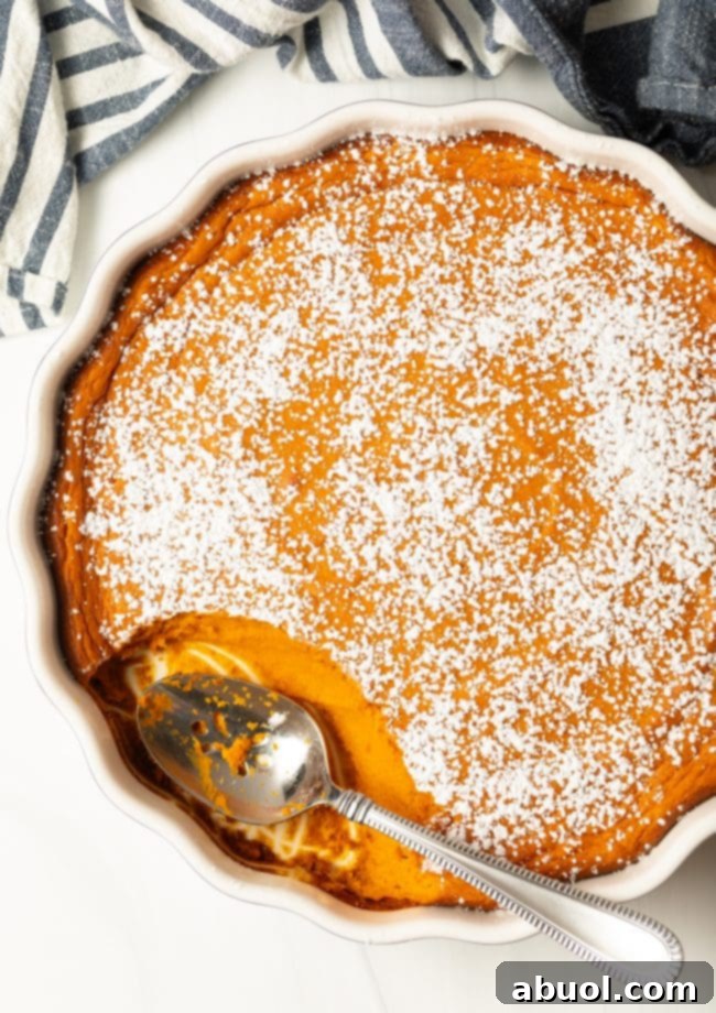 top view mashed carrot souffle casserole with powdered sugar, metal spoon taking a scoop