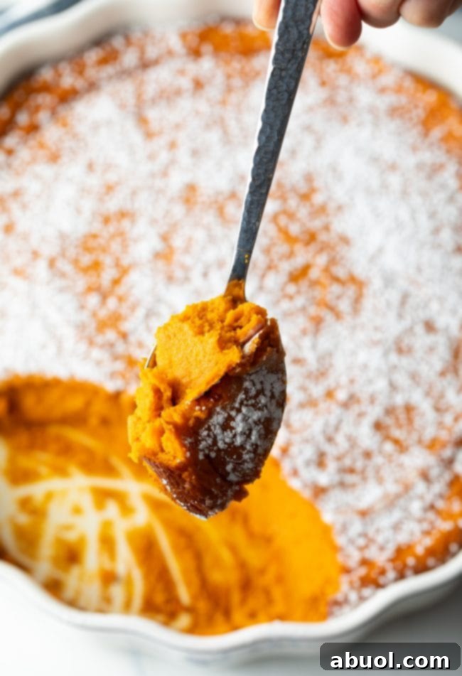 spoon with scoop of carrot souffle over full casserole in background