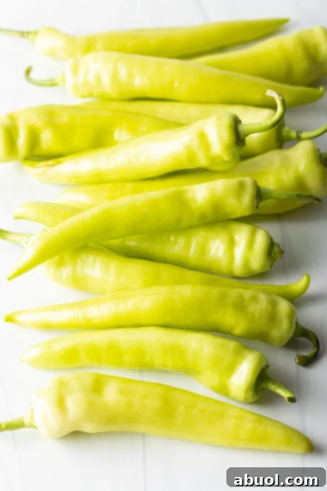 Fresh yellow and green banana peppers on a white background, ready for prep