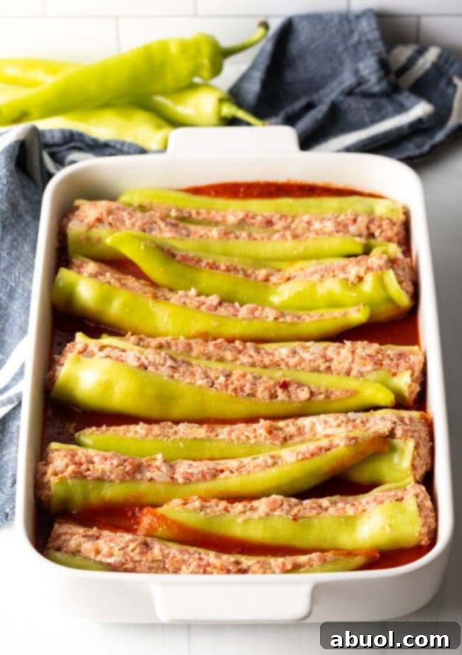 Stuffed banana peppers arranged in a baking dish with marinara, ready for the oven