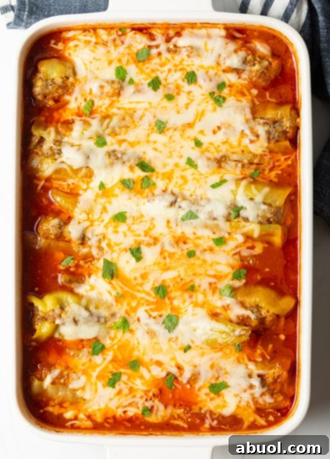 Top view of baked banana peppers in sauce and covered with cheese and parsley sprinkled on top, in a large baking dish
