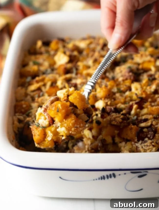 Savory Butternut Squash Casserole -
spoon scooping a helping of squash stuffing from a baking dish