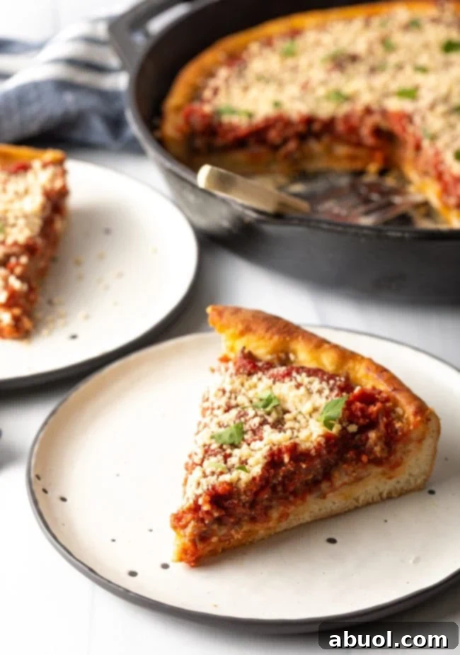 slice of deep dish pizza on a plate with cast iron in the background