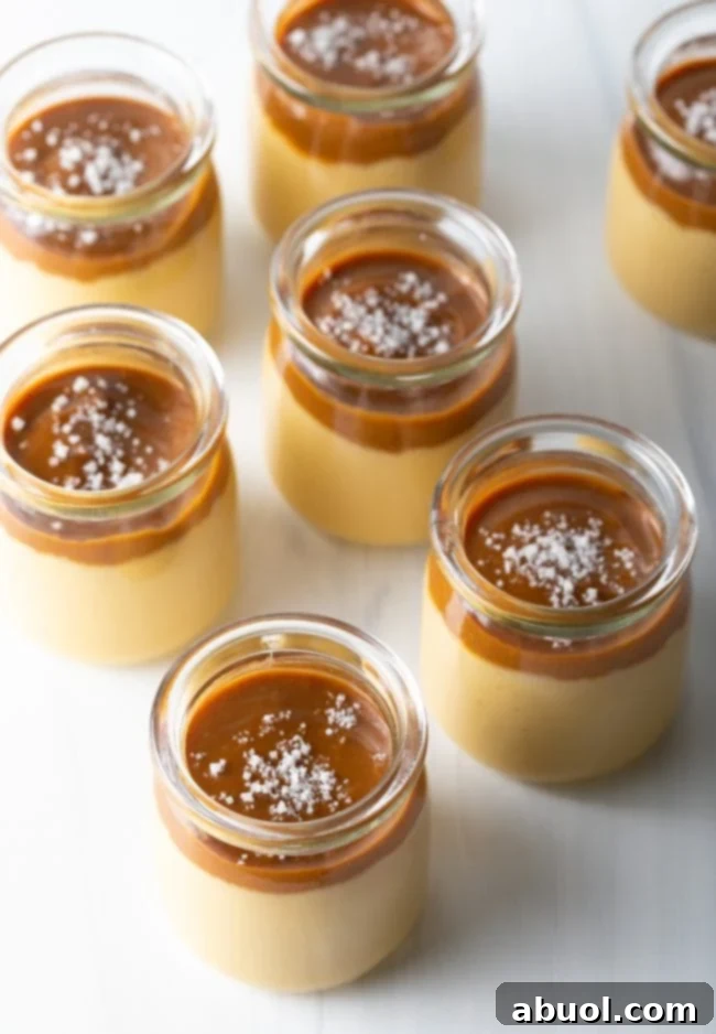 Italian Dessert Recipes - top side view of several glass jars with homemade butterscotch budino topped with glistening caramel and sea salt, arranged appealingly