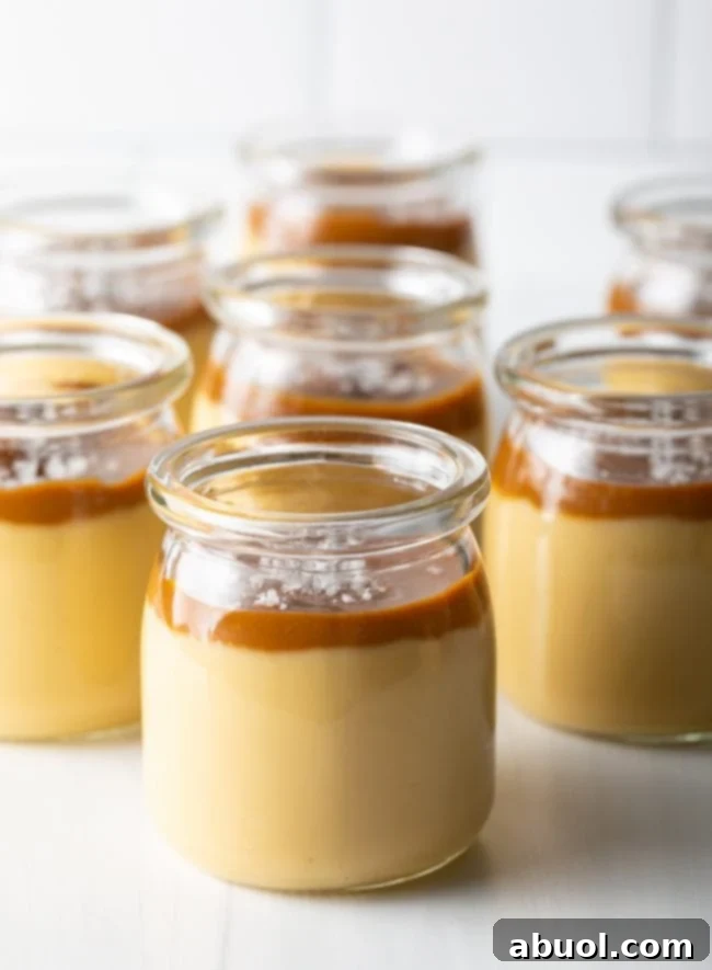 Budino Dessert Recipe - side view of several glass jars filled with layers of rich butterscotch pudding and decadent salted caramel topping